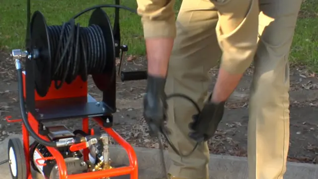 Hydro jetting machine with a hose reel and a technician guiding the hose into a drain