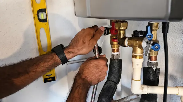 Hands connecting the water fittings of a tankless water heater with a level on the wall